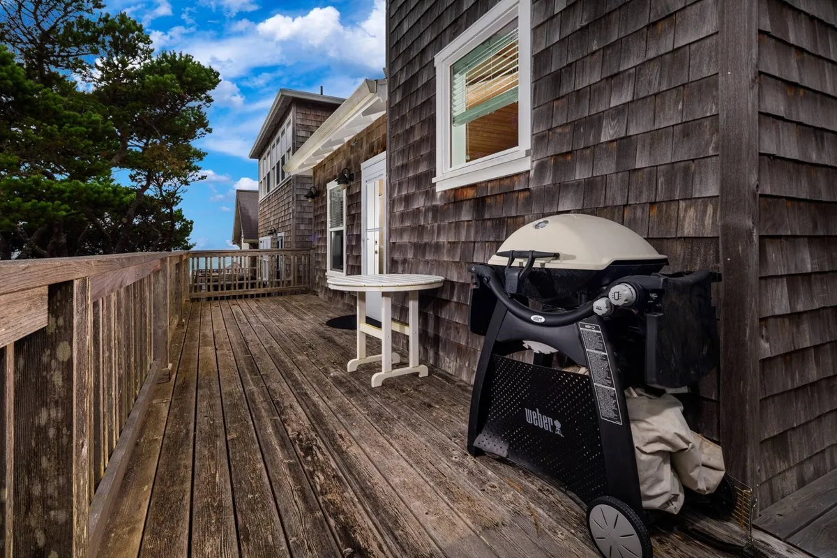 An inviting outdoor deck scene featuring a grill, table, and deck railing—ideal for socializing and relaxing. The setting is perfect for gatherings, informal meals, or evening conversations under the stars, highlighting the social aspects of resort living.